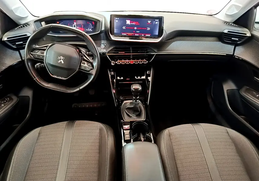 Intérieur de la Peugeot 208 PureTech 100 vue de face, tableau de bord noir avec écran tactile central et volant cuir.
