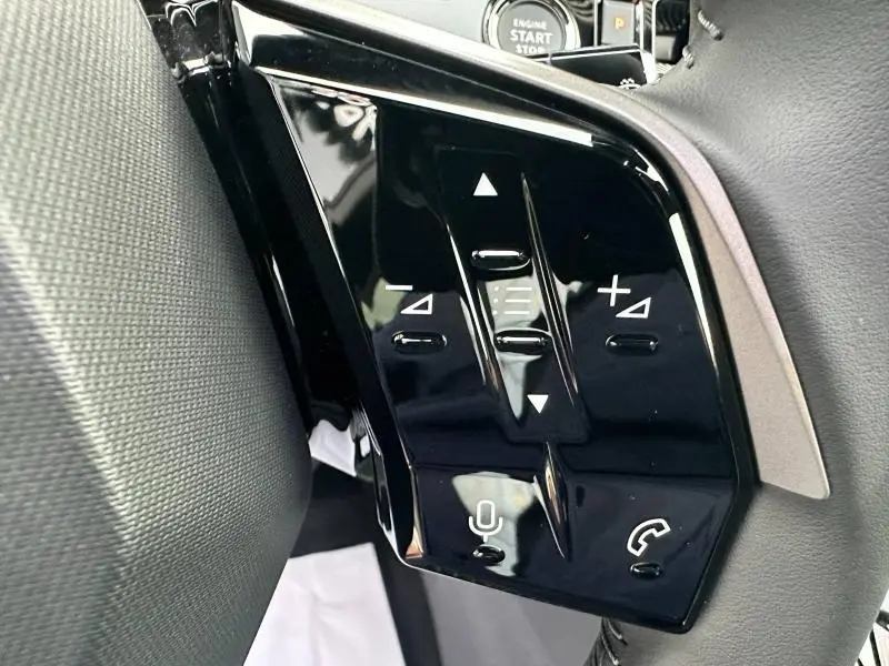 Gros plan sur les commandes noires du volant multifonction du Peugeot 3008 gris Titane, avec bouton micro et téléphone.