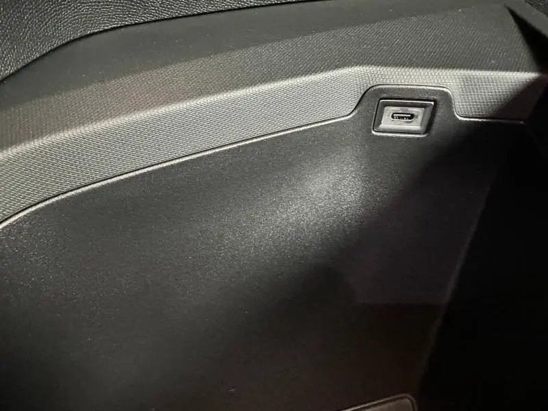 Gros plan sur la boîte à gants noire du Peugeot 3008 Hybrid 2025 avec prise USB intégrée visible.