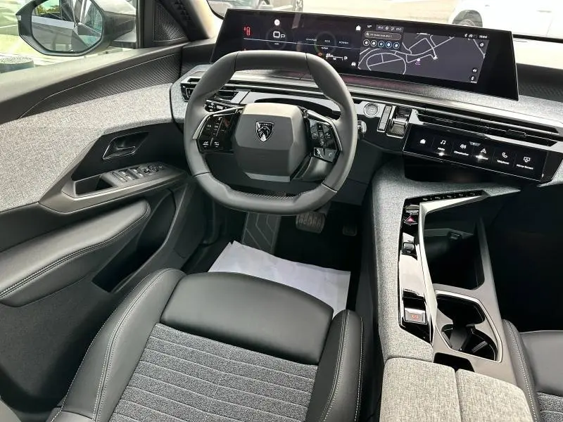 Intérieur avant du Peugeot 3008 Hybrid 2025, vue du siège conducteur avec volant compact et écran tactile panoramique.
