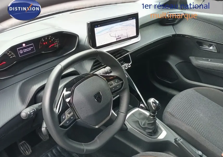 Vue intérieure côté conducteur du Peugeot 208 gris Artense, avec volant cuir multifonction et écran tactile central.