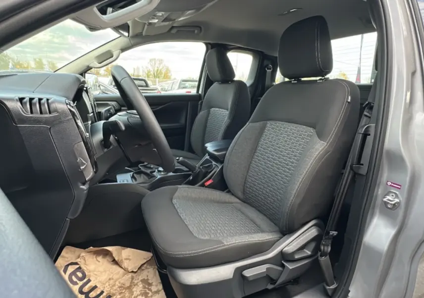 Vue intérieure côté conducteur du Ford Ranger gris iconic 2026, montrant les sièges avant et le volant multifonctions en cuir.