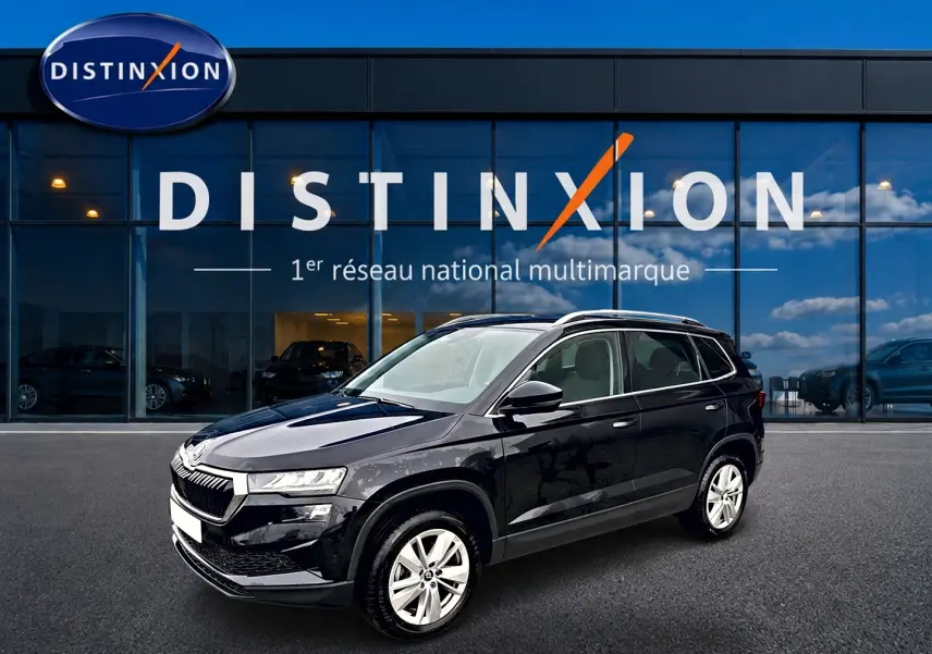 SKODA KAROQ noir 3/4 avant droit, jantes alu et barres de toit visibles devant vitrine Distinxion.