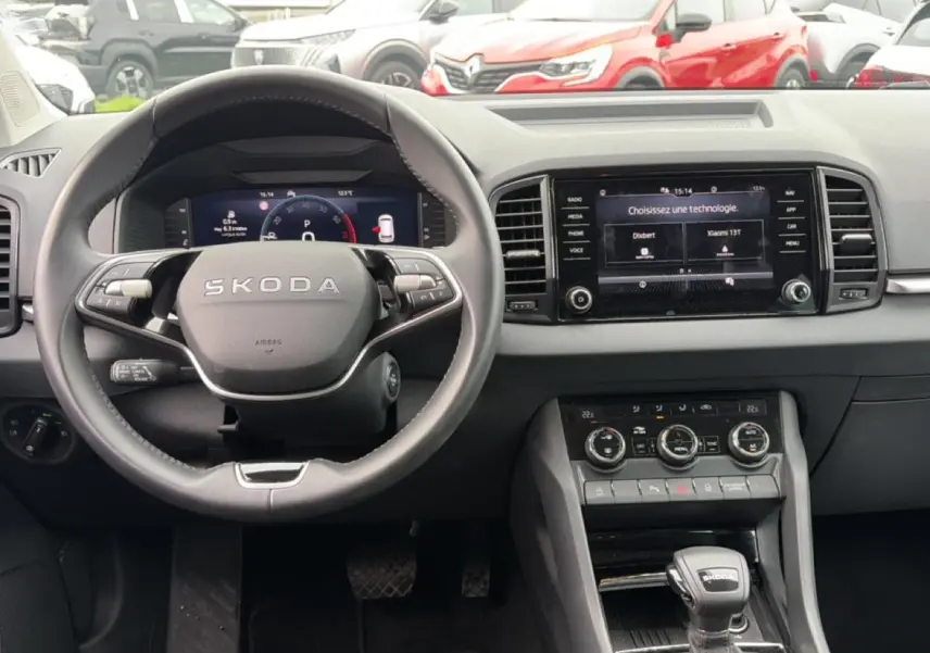 Vue intérieure frontale du tableau de bord et volant noir de la Skoda Karoq 1.5 TSI 2025 avec écran tactile et commandes au volant.