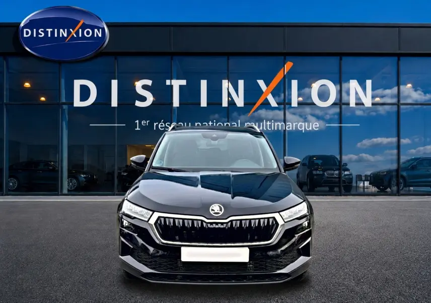 Vue avant d'un Skoda Karoq noir 2025 avec calandre chromée et phares LED devant une vitrine Distinxion.