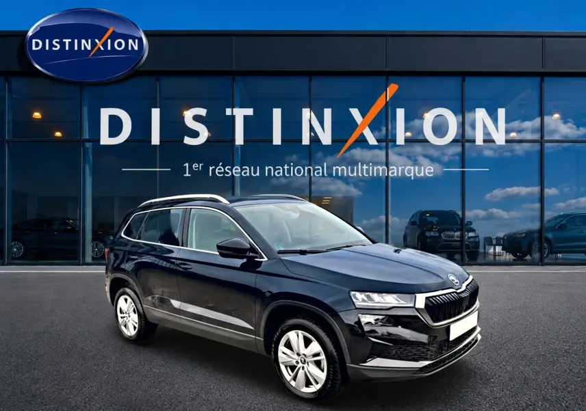 SUV Skoda Karoq noir en 3/4 avant droit, avec jantes alu, devant une vitrine Distinxion.