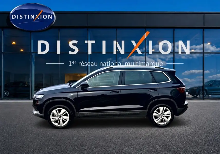 Vue latérale droite d'un Skoda Karoq noir 2025 avec jantes alu, devant une vitrine Distinxion.