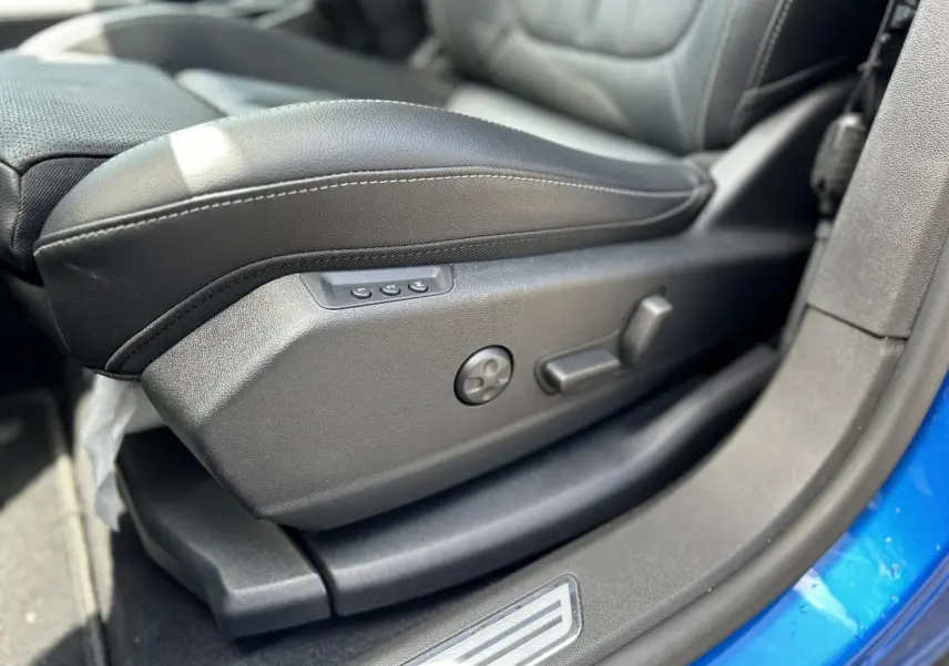Gros plan sur le siège conducteur électrique en cuir noir avec réglages latéraux, intérieur d’un Opel Grandland Bleu Vertigo.
