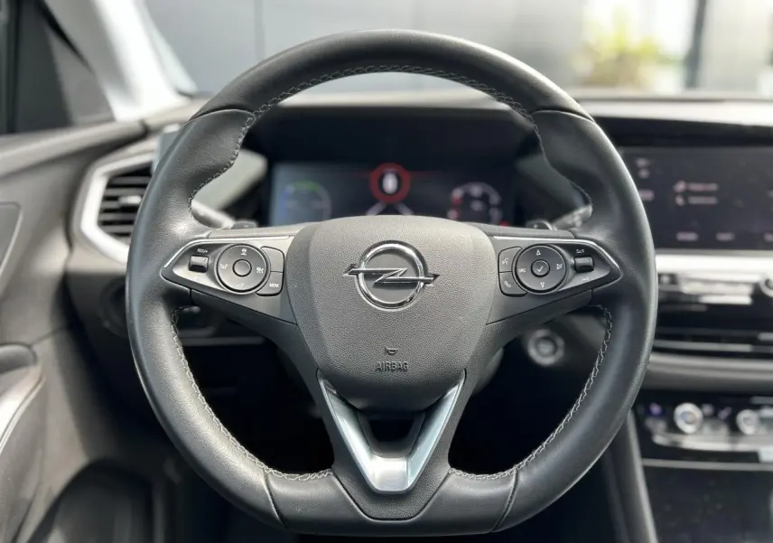 Volant en cuir multifonction de l’Opel Grandland 1.6 Hybrid 225, vue frontale centrée sur le logo Opel