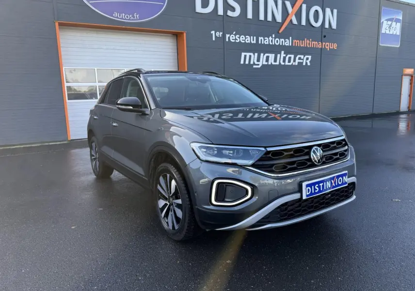 Volkswagen T-Roc gris Indium métallisé en 3/4 avant droit, avec calandre noire et feux LED allumés.
