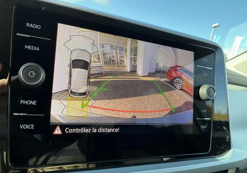 Écran tactile intérieur montrant la caméra de recul du Volkswagen T-Roc gris Indium métallisé en stationnement.