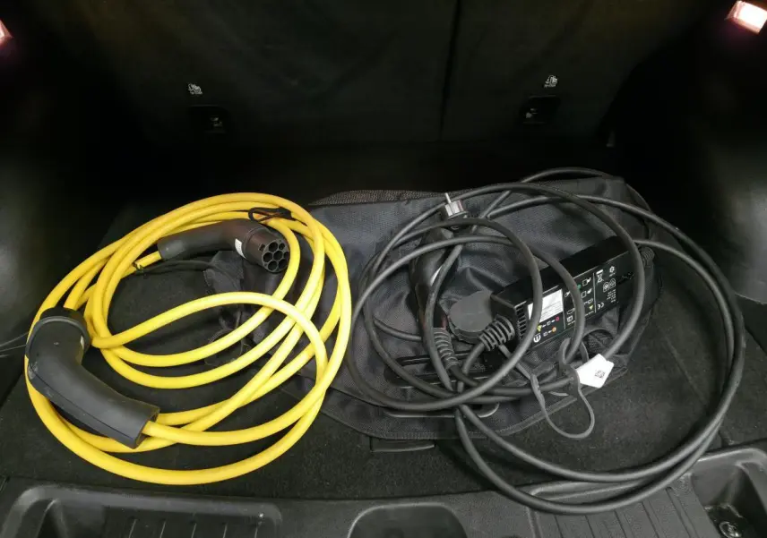 Câbles de recharge jaune et noir dans le coffre d'un Jeep Compass 2024 noir hybride rechargeable.