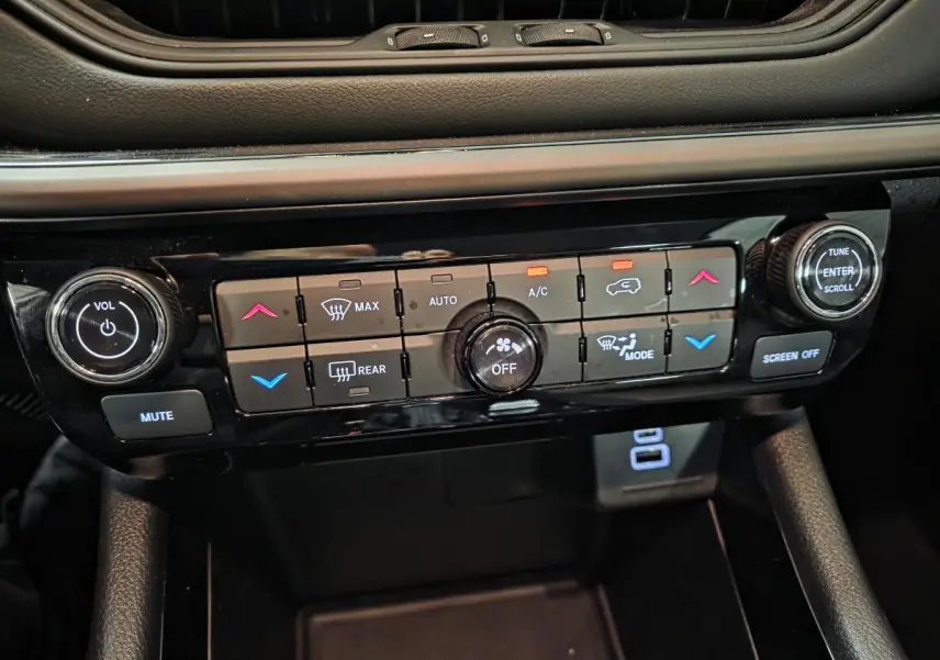 Tableau de bord du Jeep Compass 2024 montrant les commandes de climatisation et audio en plan rapproché noir brillant.