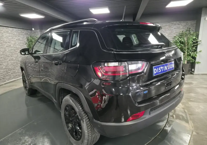Vue 3/4 arrière droite du Jeep Compass noir brillant avec jantes noires et logo 4xe sur le hayon.
