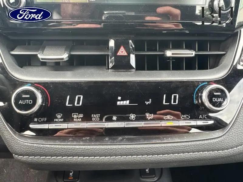 Vue rapprochée du tableau de bord de la Toyota Corolla gris Manhattan, montrant les commandes de climatisation automatique bi-zone.