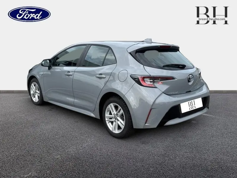 Vue 3/4 arrière droite d'une Toyota Corolla gris Manhattan métallisé avec feux arrière LED et jantes alu.