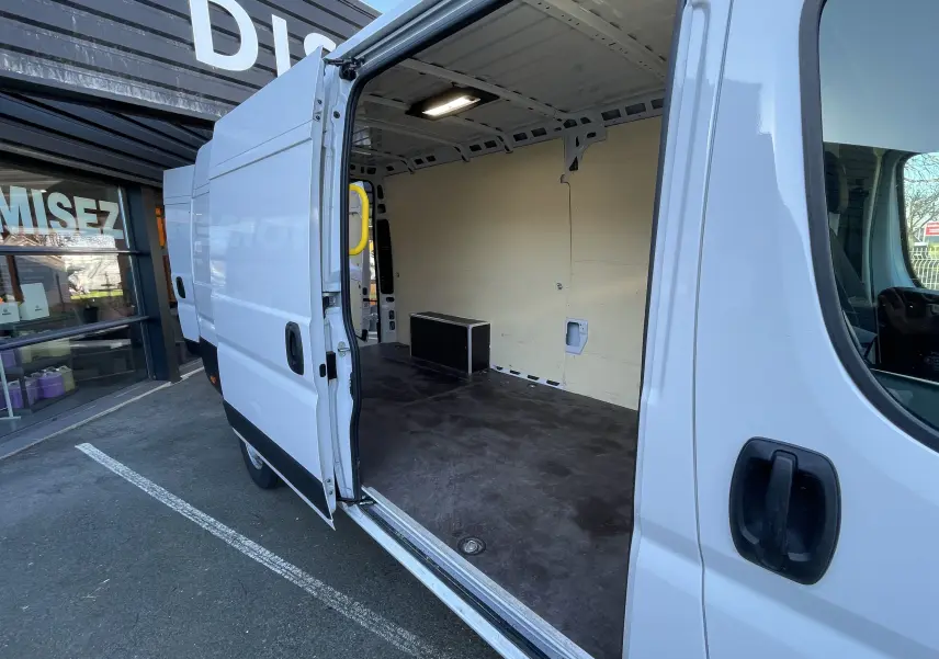 Vue latérale droite du Peugeot Boxer Fourgon blanc 2025 avec porte coulissante ouverte montrant l’espace de chargement vide.
