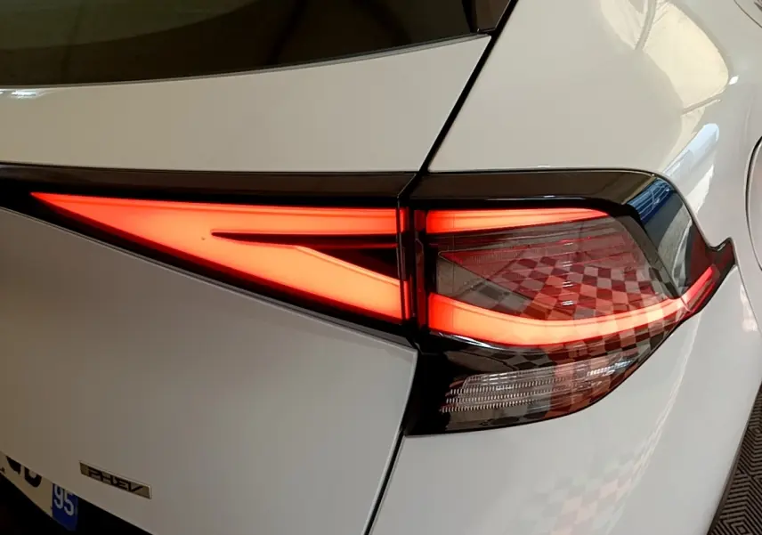 Gros plan sur le feu arrière droit allumé d’un KIA SPORTAGE blanc hybride rechargeable, détail du design lumineux moderne.