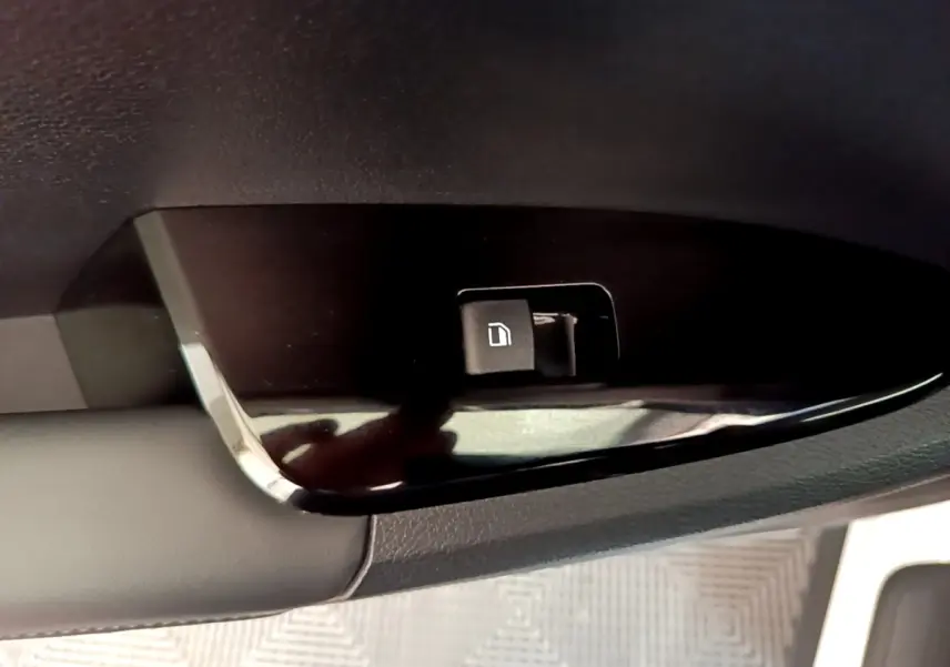 Gros plan sur le bouton de verrouillage des portes côté conducteur du Kia Sportage blanc, intérieur noir.