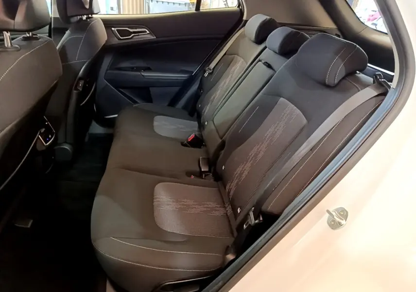 Vue intérieure côté droit sur la banquette arrière noire du Kia Sportage blanc, avec appuie-têtes et ceintures visibles.