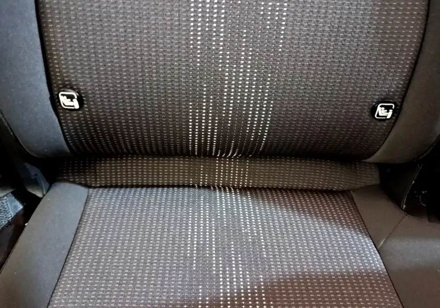 Gros plan sur la banquette arrière en tissu gris foncé avec motifs clairs et fixations Isofix visibles sur une KIA SPORTAGE blanche.