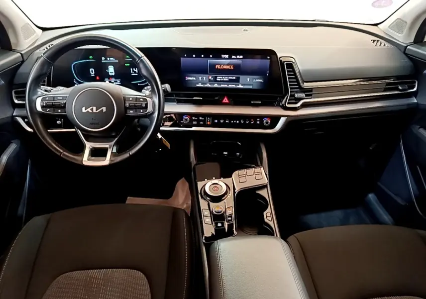 Vue intérieure avant du tableau de bord du Kia Sportage 2022, avec volant cuir et écran tactile large noir.