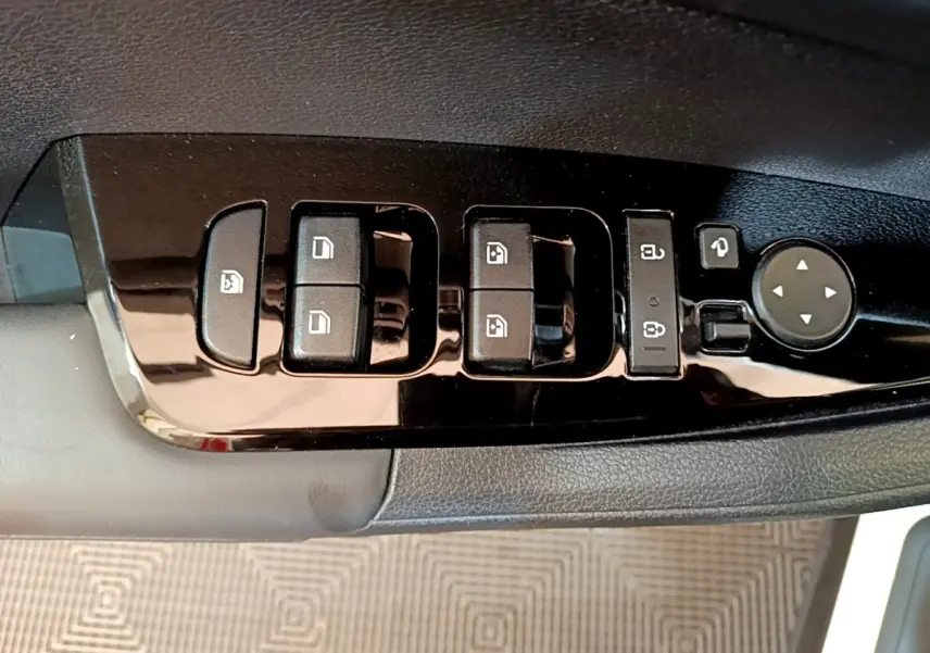 Gros plan sur les commandes de lève-vitres et rétroviseurs côté conducteur du KIA Sportage blanc 2022.
