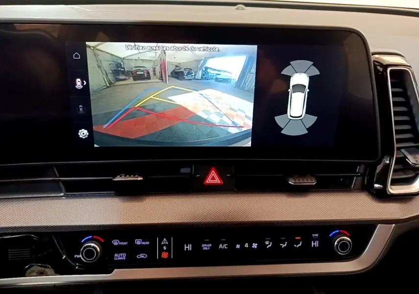 Vue rapprochée de l'écran tactile central du Kia Sportage blanc 2022 montrant l'aide au stationnement arrière.