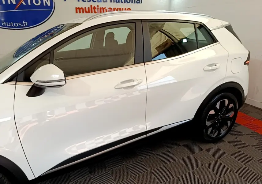 Profil droit du KIA SPORTAGE blanc 2022 hybride rechargeable, avec rétroviseur et jante noire au design moderne.