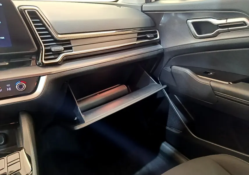 Intérieur du Kia Sportage 2022, vue côté passager sur la boîte à gants ouverte et tableau de bord noir.