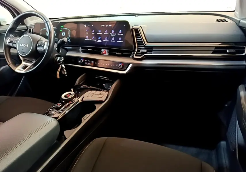 Intérieur noir du Kia Sportage 2022 vu côté conducteur, avec tableau de bord digital et console centrale moderne.