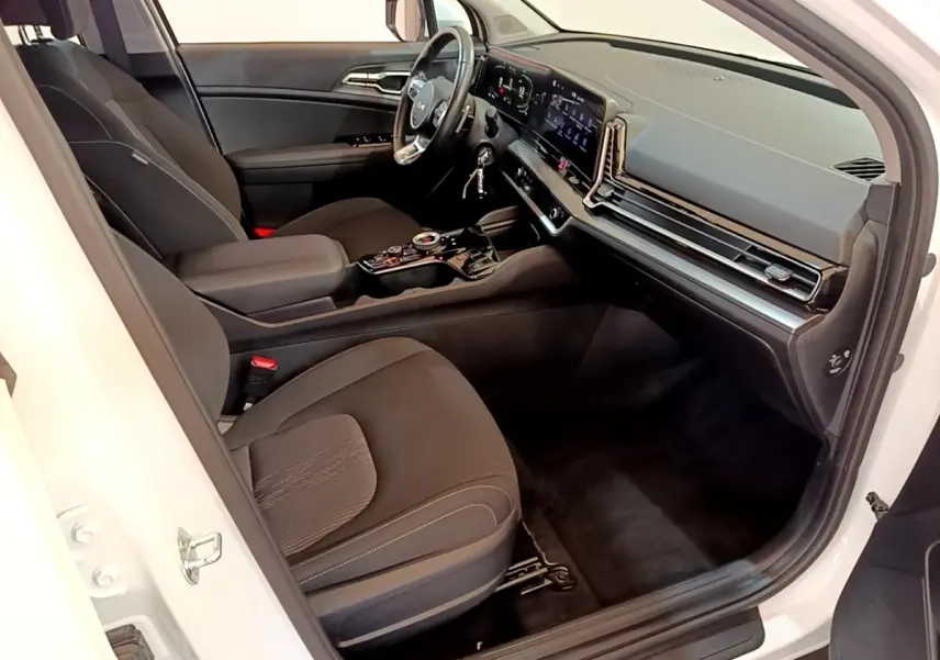 Vue intérieure côté conducteur du Kia Sportage blanc 2022, avec tableau de bord numérique et sièges noirs.