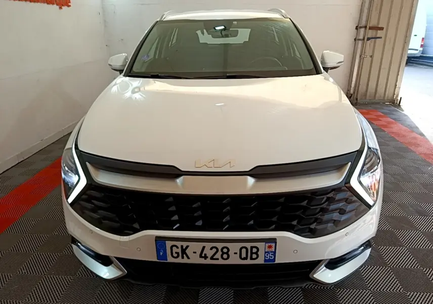 Vue avant d'un KIA Sportage blanc 2022 avec calandre noire et phares LED en V distinctifs.