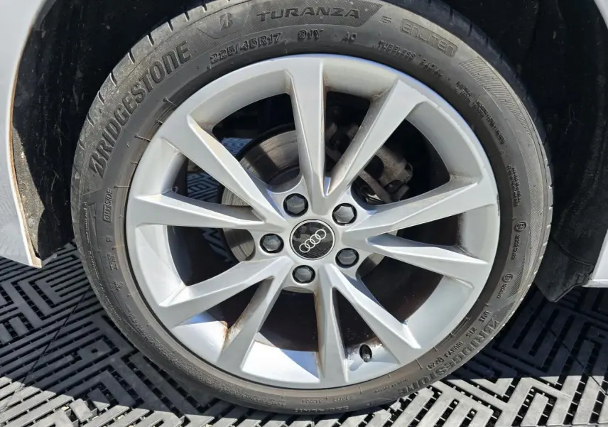 Gros plan sur la jante alliage 5 branches parallèles de l'Audi A3 Sportback blanc Arkona, pneu Bridgestone visible.