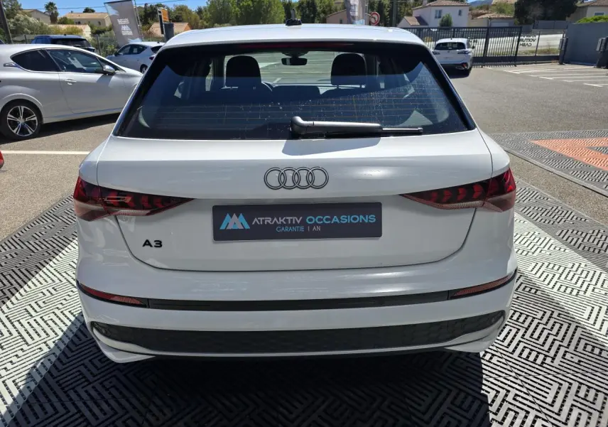 Vue arrière d'une Audi A3 Sportback 2024 en blanc Arkona avec feux arrière LED et logo Audi visible.