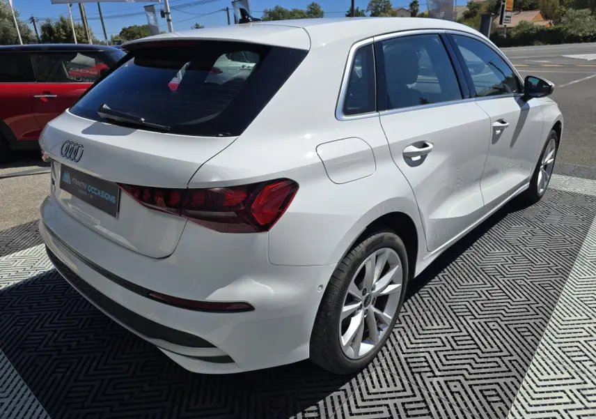 Audi A3 Sportback blanc Arkona vue 3/4 arrière droit, avec jantes alliage 5 branches et feux arrière LED distinctifs.