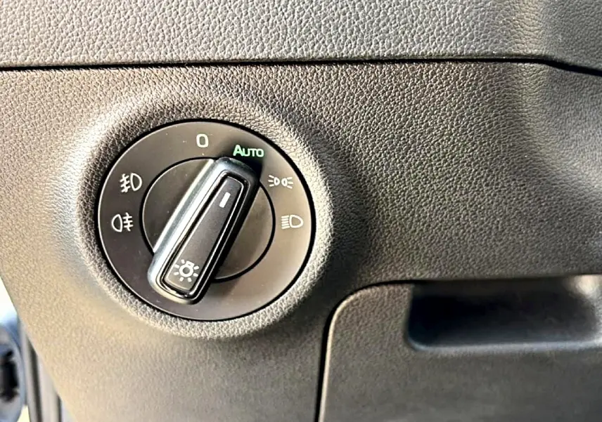 Gros plan sur le bouton de commande des phares du Skoda Karoq 1.5 TSI 150 gris, intérieur noir texturé.