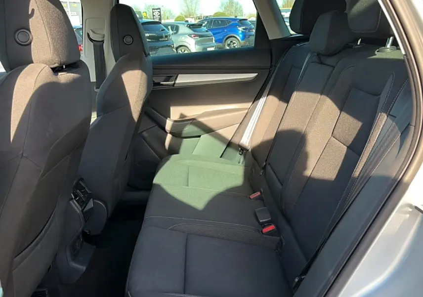 Vue intérieure côté droit des sièges arrière noirs du Skoda Karoq gris 2025 avec porte ouverte et lumière naturelle.