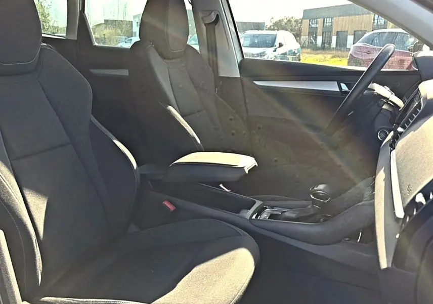 Vue intérieure côté droit du Skoda Karoq 2025, sièges tissu gris et accoudoir central avec rangement.