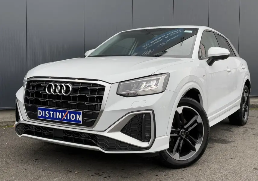 Audi Q2 30 TFSI S-Line blanc Glacier en 3/4 avant droit, avec calandre noire et jantes alliage noires polies.