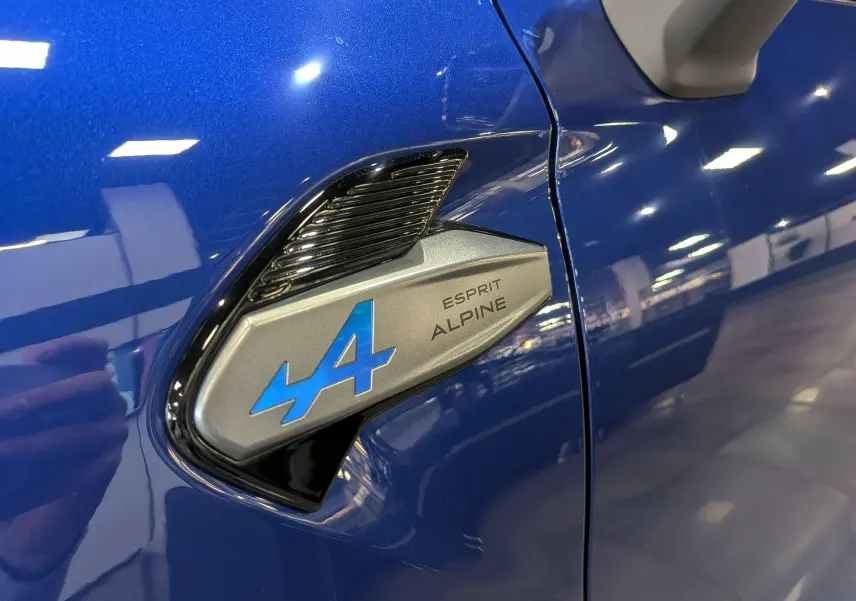 Gros plan sur l'emblème Esprit Alpine bleu sur la carrosserie Bleu Iron du Renault Captur 2025 côté avant droit.