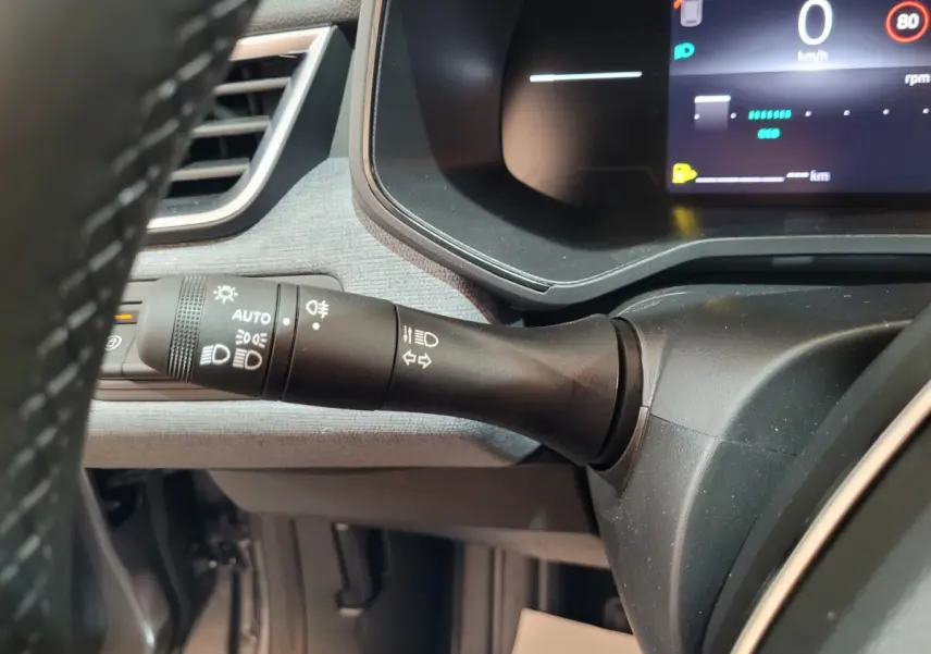 Gros plan sur la commande d'éclairage à gauche du volant dans l'habitacle de la Renault Clio gris foncé 2025.