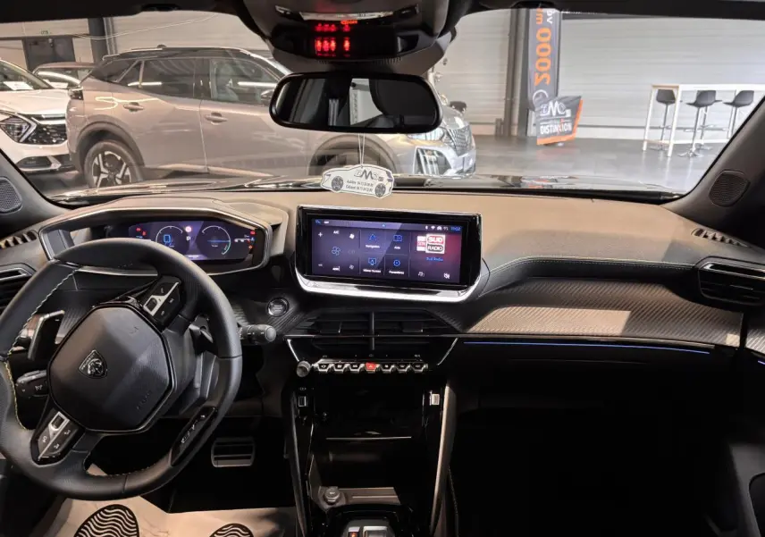 Vue intérieure avant du Peugeot 2008 blanc 2025, mettant en valeur le tableau de bord numérique et l'écran tactile central.