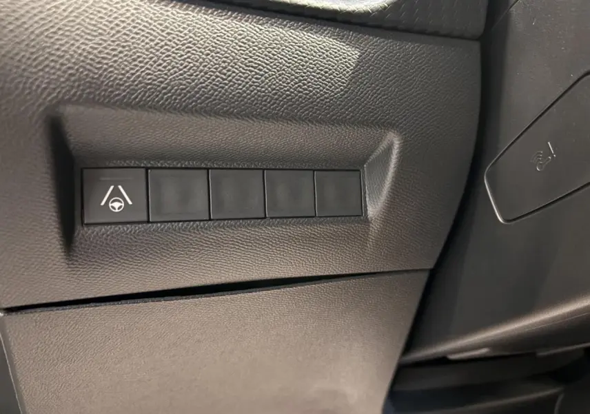 Gros plan sur les boutons de commande à gauche du volant du Peugeot 2008 blanc hybride 2025, avec fonction assistance au maintien de voie.