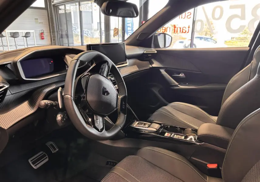 Intérieur noir du Peugeot 2008 hybride 2025 vu côté conducteur, avec volant compact et écran central tactile.