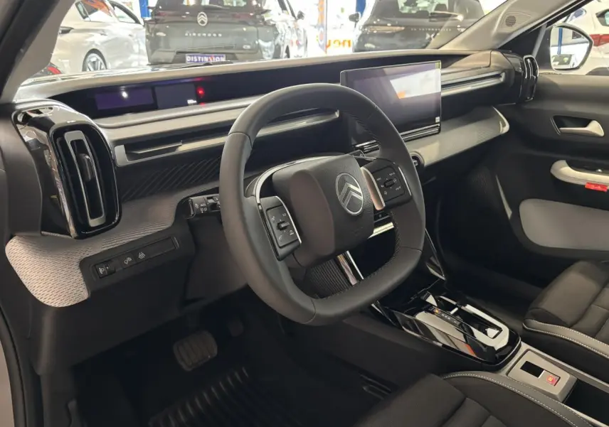 Vue intérieure côté conducteur du Citroën C3 Aircross 2026, volant carré et tableau de bord moderne noir et gris.