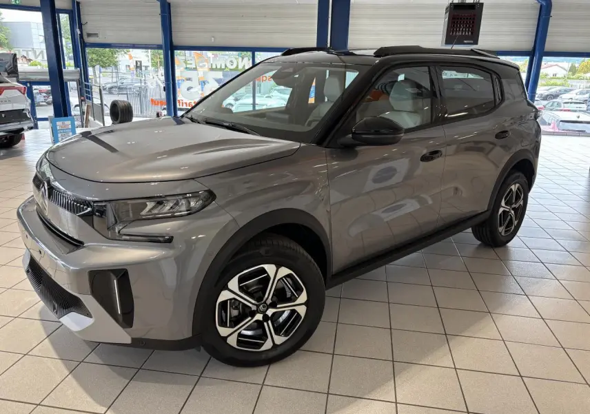 Citroën C3 Aircross 2026 gris métallisé avec toit noir, vue 3/4 avant droit en showroom intérieur.