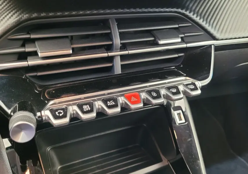 Gros plan sur la console centrale noire de la Peugeot 208 2023 avec boutons de commande et prise USB visible.