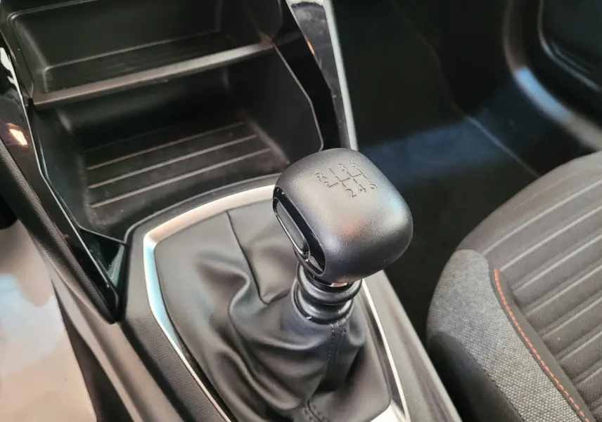 Le levier de vitesses manuel noir de la Peugeot 208 gris foncé, vu en gros plan côté passager.
