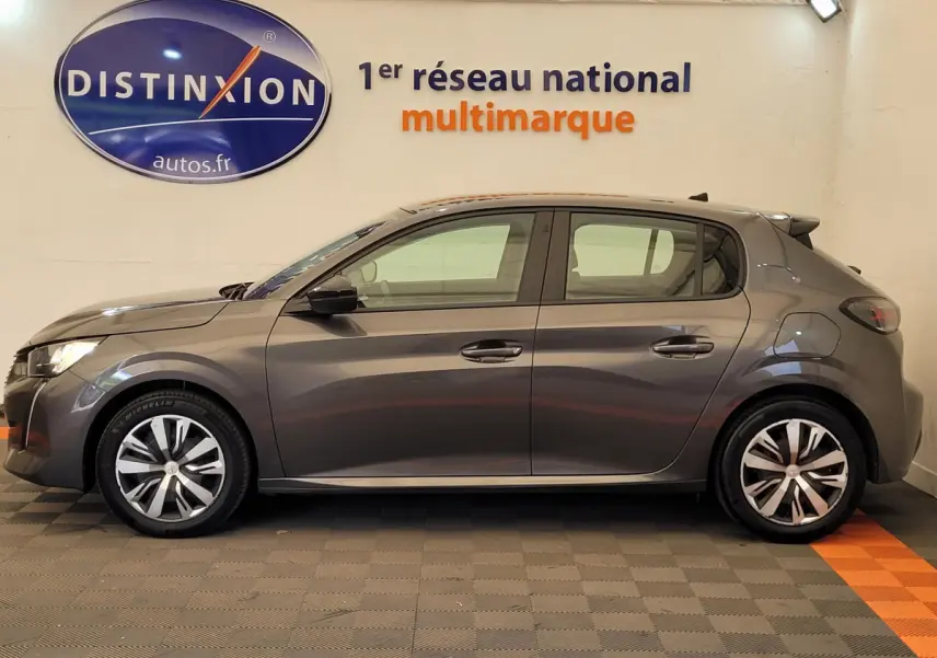 Profil latéral droit d'une Peugeot 208 BlueHDi 100 S&S Active Pack gris foncé stationnée en intérieur.
